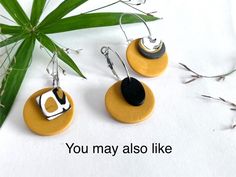 three earrings with black and white designs on them sitting next to a green plant that says you may also like