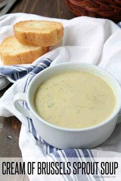 a bowl of cream of brussels sprout soup next to two slices of bread