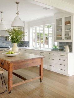 a kitchen with white cabinets and an island in front of the countertop, along with two stools