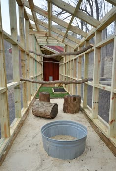 the inside of a chicken coop with wooden posts and wood logs in front of it