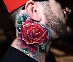 a man with a rose tattoo on his neck is looking at the camera while wearing a red hat