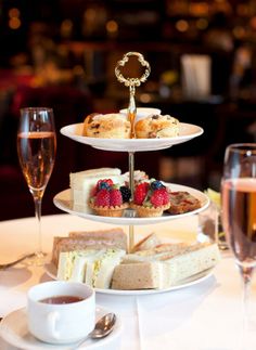 three tiered trays filled with cakes and pastries next to glasses of champagne