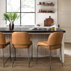 three chairs are sitting in front of a kitchen island with a potted plant on it