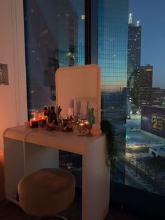 a vanity table with candles on it in front of a window overlooking a cityscape