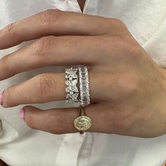 a woman's hand with three different rings on her fingers and one ring in the middle