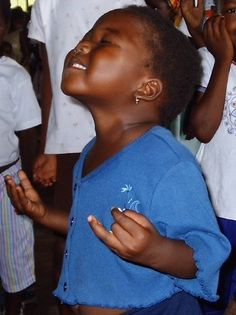 a little boy that is standing up with his eyes closed and hands in the air