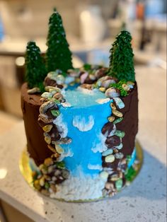 a cake decorated with trees and rocks on a counter