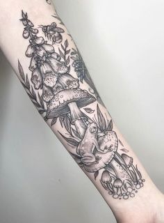 an arm tattoo with mushrooms and flowers on it