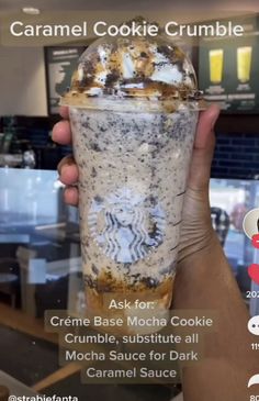 someone holding up a starbucks cookie crumble drink in front of a counter top