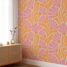 an orange and pink wallpaper in a living room with a dresser next to it