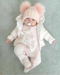 a baby doll wearing a pink outfit and hat with pom - poms on it's head