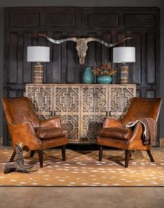 two brown leather chairs sitting in front of a wall with an animal head on it