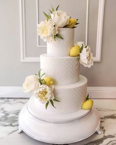 a three tiered white cake with lemons and flowers