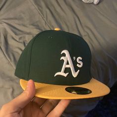 a baseball cap with the letter a's on it is being held up by someone