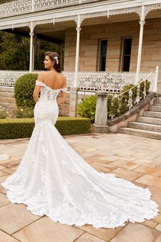 a woman in a wedding dress is standing on the ground near some steps and bushes