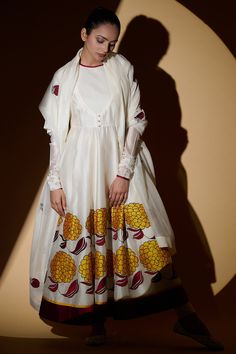 Ivory anarkali in chanderi base with contrast mustard yellow and burgundy floral appliqued work. Paired  with dupatta and lycra net churidar.
Components:3
Pattern:Applique
Type of Work:Floral Motifs
Neckline:Round
Sleeve Length:Gathered Sleeves
Fabric:Chanderi, Lycra Net
Color:White
Other Details:
Polka dot hem sleeves
Textured yoke
Front potli buttons
Contrast hem anarkali
Occasion:Puja - Aza Fashions Ivory Anarkali, Chanderi Anarkali, Yellow And Burgundy, Fabric Paint Shirt, White Kurta, Party Suits, Gathered Sleeves, Applique Embroidery, Indian Fashion Designers