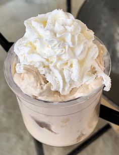 an ice cream sundae with whipped cream on top is sitting on a glass table