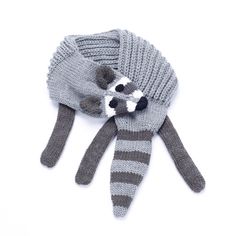 a knitted raccoon hat and mitten laying on top of each other