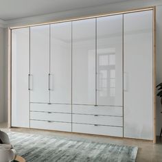 a large white closet with drawers and doors in a living room next to a rug