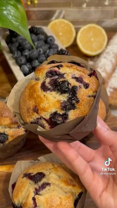 blueberry muffins in paper cups on a table with fresh fruit and bread