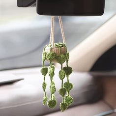 a cell phone hanging from the dashboard of a car with green crocheted decorations