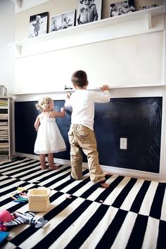 two young children are playing on the floor in their room with black and white striped carpet