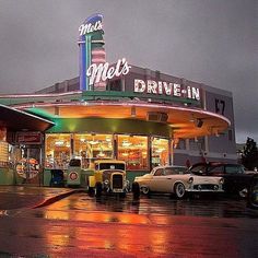 cars are parked in front of a drive - in movie theater on a rainy day