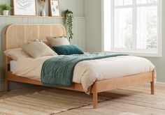 a bed sitting on top of a wooden floor next to a table with a vase