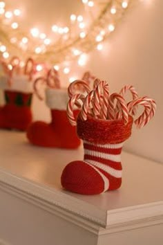 candy canes are wrapped in red and white striped stockings on a mantle with candles