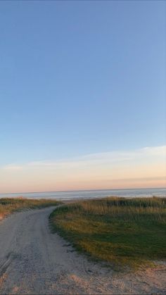 an empty dirt road next to the ocean