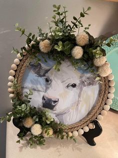 a white cow is surrounded by greenery and pom - poms on a table