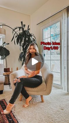 a woman sitting on a chair in a living room next to a potted plant