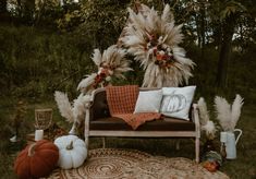 a couch sitting on top of a rug covered in lots of pillows and feathers next to trees