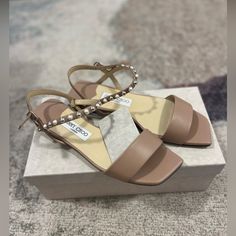 New With Box And Dust Bag Beige Flat Sandals For Evening, Designer Beige Sandals With Single Toe Strap, Designer Beige Ankle Strap Sandals, Designer Beige Sandals With Open Heel, Designer Beige Open Heel Sandals, Neutral Beige, Jimmy Choo Shoes, Pearl Studs, Flat Sandals