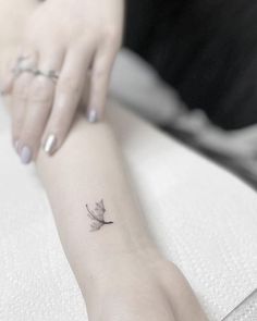 a woman's arm with a small bird tattoo on the left side of her wrist