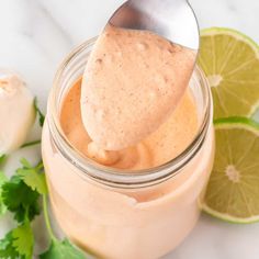 a spoon full of mayonnaise with cilantro and limes in the background