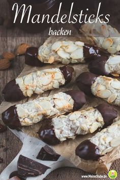 several pieces of chocolate covered cookies sitting on top of a wooden table next to nuts