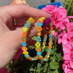 Handmade, beaded, flower, hoop earrings. Colorful flowers in oranges, blue, teal, and yellow mounted onto rose gold colored stainless steel hoops. They are lightweight with a latch closure, and have a summery color scheme. About 6.5 cm in diameter. Trending Earrings, Flower Hoop Earrings, Earrings Colorful, Earring Trends, Beaded Hoop Earrings, Blue Teal, Rose Gold Color, Jewelry Earrings Hoops, Colorful Flowers