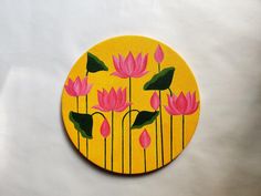 a yellow circle with pink flowers painted on the front and bottom, sitting on a white surface