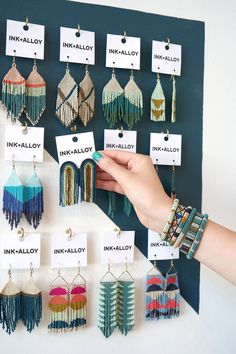 there are many different earrings hanging on the wall with name tags attached to them,