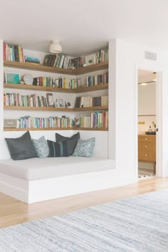 a living room filled with furniture and bookshelves next to a doorway that leads to a hallway