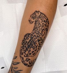 a tattoo on the leg of a person with a cheetah and leaves design