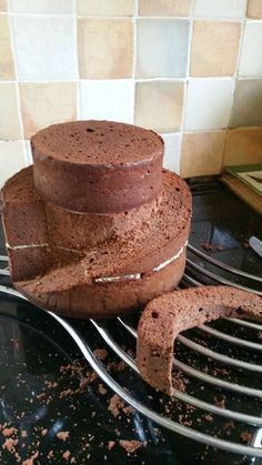 three chocolate cakes stacked on top of each other in front of a tile backsplash