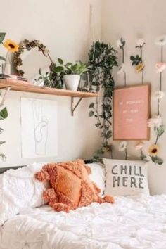 a white bed topped with lots of pillows and flowers next to a shelf filled with plants