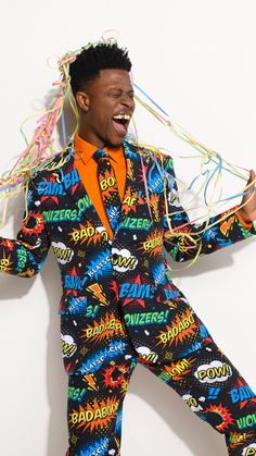 a man in a colorful suit and orange shirt is dancing with streamers on his head