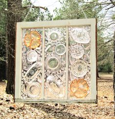 an artisticly designed glass panel in the woods with leaves and flowers on it's sides