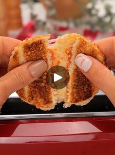 someone holding up a grilled cheese sandwich in front of a red grilling pan