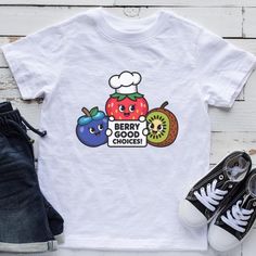 Encourage healthy eating with this adorable kids' t-shirt featuring fun cartoon fruits and the playful message, "Berry Good Choices!" This cute and colorful graphic tee is perfect for promoting nutrition and making healthy food choices fun for children. Ideal for parents, teachers, or health advocates, this shirt inspires kids to embrace fruits and healthy habits. A great gift for young food lovers, school events, or any occasion where promoting healthy lifestyles is important. Thank you for visiting my shop. Please contact me if you have any questions or requests. Not the design, colour or size you need? Each item is made individually so I can make anything you want. Just send a message with your ideas. This item is custom designed especially for you so I cannot accept returns but if you Cute Crew Neck T-shirt With Fruit Design, Cute White T-shirt With Fruit Print, Fun White T-shirt With Fruit Print, Fun Short Sleeve T-shirt With Fruit Print, Crew Neck Fruit Design Graphic Tee, Graphic Tee With Fruit Design And Crew Neck, Fruit Design Graphic Tee With Crew Neck, Crew Neck Graphic Tee With Fruit Design, Crew Neck Cotton T-shirt With Fruit Design