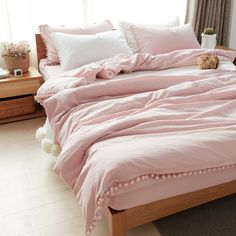 a bed with pink sheets and pillows in a bedroom