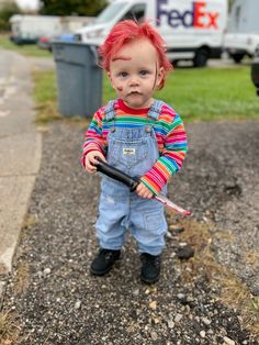 a toddler with red hair and overalls holding a toothbrush in his mouth